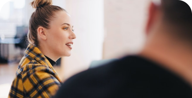 Side view of a white woman in a plaid top speaking.