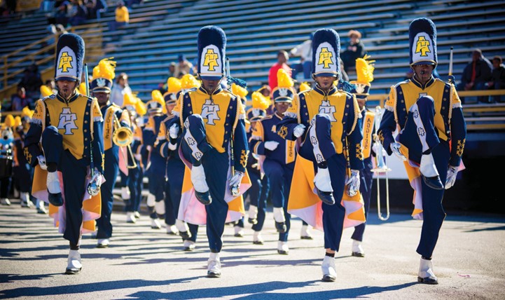 North Carolina A&T marching band members high step with other band members marching behind them.