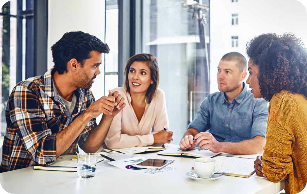 A team of four professionals sit around a table having a discussion.