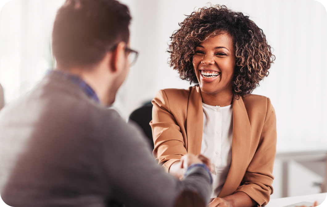 A smiling professional black woman shakes hands with a business parter.