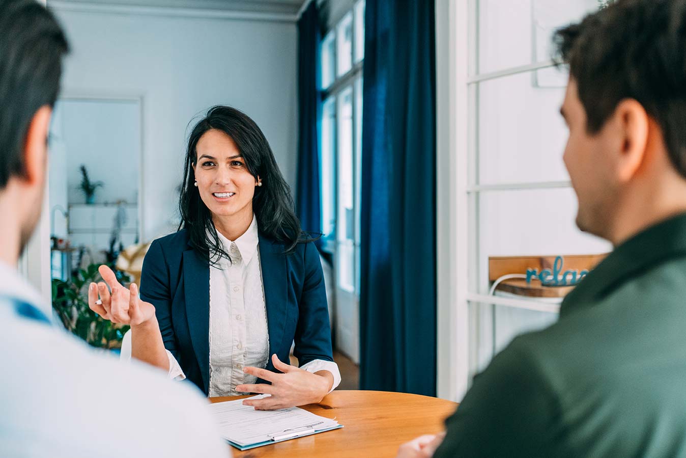 executive-search A professional young woman seated at a table explains something to the two people sitting across from her.